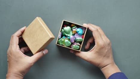 men hand pick candy from a box on table ,