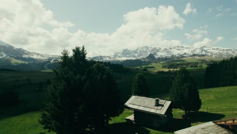 alpine valley with wooden huts and snow-capped mountains