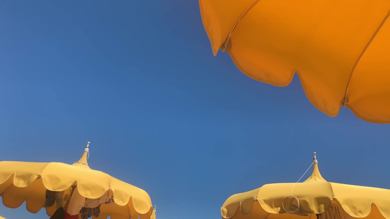 노란색 비치 파라솔의 오른쪽에서 왼쪽으로 패닝하고 배경의 맑고 푸른 하늘, 우크라이나 색상 개념