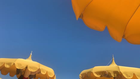 Schwenken-Von-Rechts-Nach-Links-Von-Gelben-Sonnenschirmen-Und-Klarem-Blauem-Himmel-Im-Hintergrund,-Ukrainisches-Farbkonzept