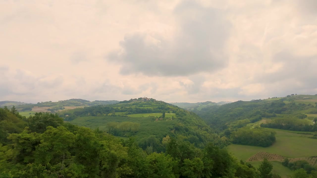 Ampia inquadratura statica cattura nuvole in movimento sopra dolci colline e vigneti in Piemonte, Italia