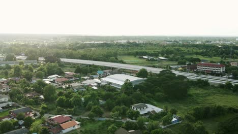 aerial wild view of railway crossing bridge and tree forest near side with traffic on the road in khonkaen, thailand