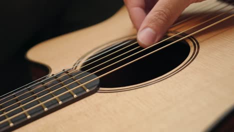 tuning an acoustic guitar by plucking the strings - close up