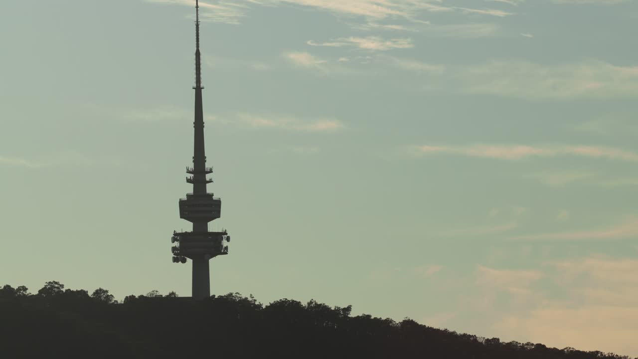 A slow zoom out unveils the Canberra Tower silhouetted against the early morning sky, capturing serenity and scale