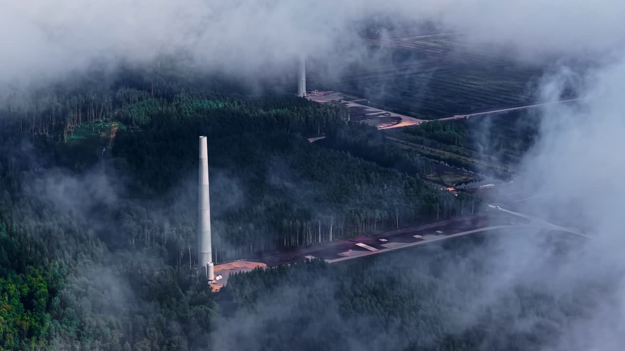 Bidikan drone yang menunjukkan progres konstruksi taman angin energi terbarukan melalui awan yang bergerak