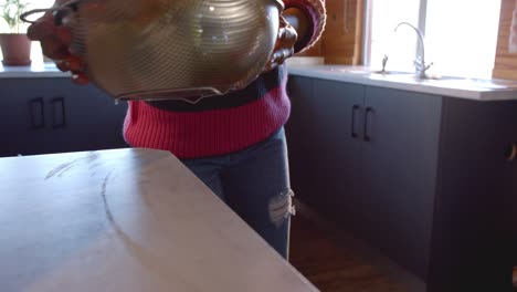 Mid-section-of-african-american-woman-rinsing-vegetables-in-sunny-kitchen,-in-slow-motion