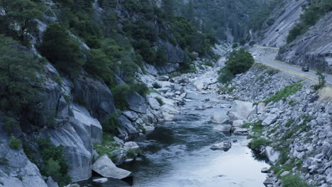 Stunning-rocky-canyon-with-peaceful-river-flowing-at-bottom,-forward-aerial