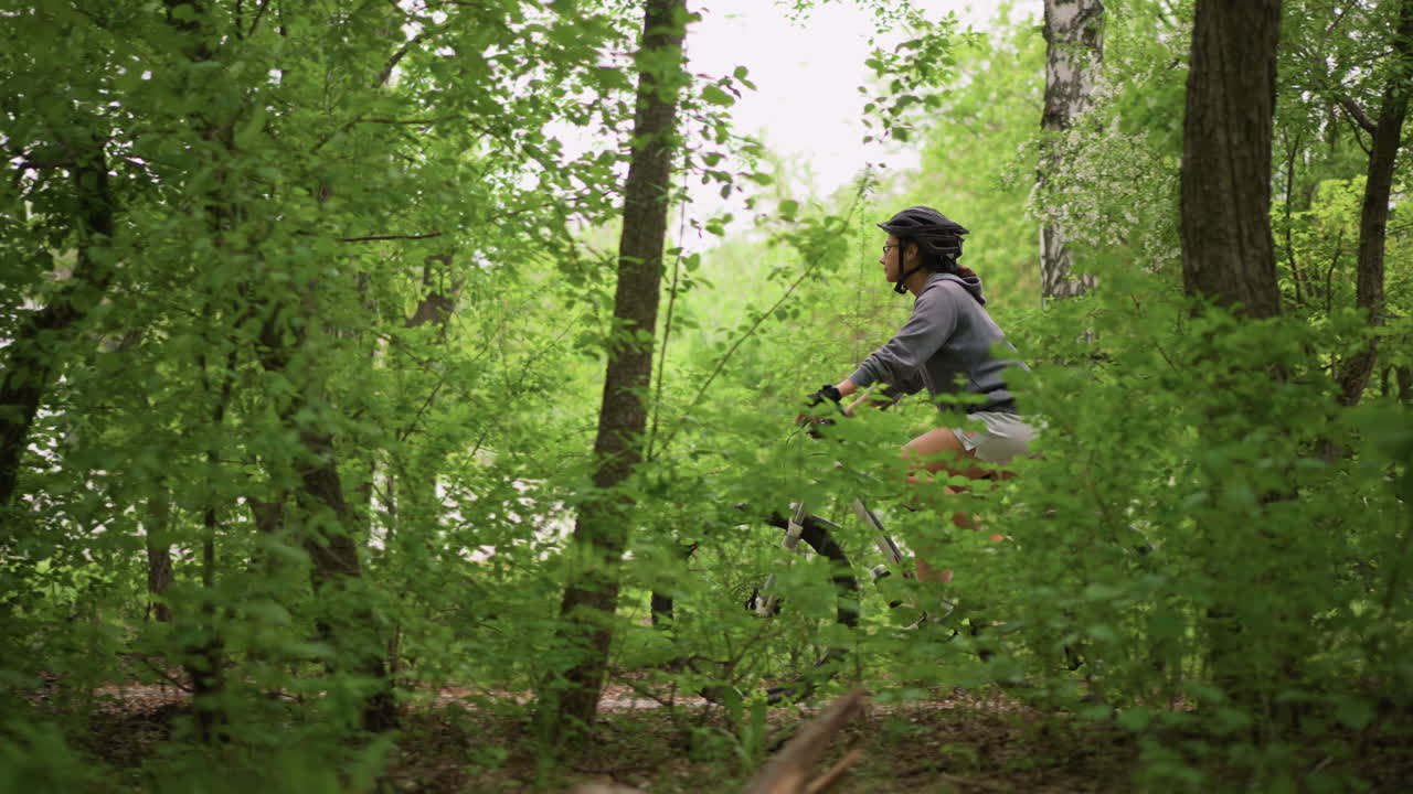 Woman Riding Bicycle Along Lakeside Path Framed By Birch Trees, Steady Cadence And Upright Posture, Helmet Fitted, Green Foliage And Reflective Water In Background, Energetic Yet Peaceful Park Ride