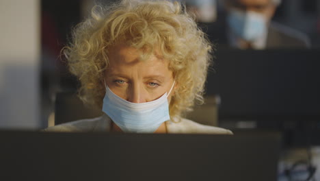 woman working at computer in office during pandemic