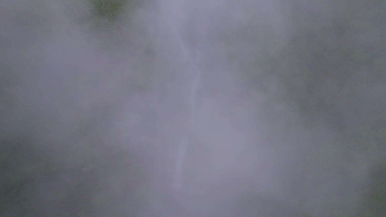 드론은 구름 속을 날아다니며 언덕과 폭포의 구름이 가득한 풍경을 드러니다. - 네팔 어드벤처 4k