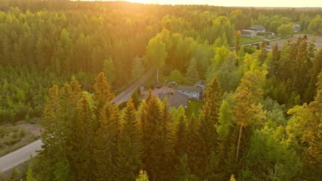 Vista-Aérea-Inclinada-Hacia-Una-Casa-Alimentada-Por-Energía-Solar-En-Medio-De-Un-Bosque-Iluminado-Por-El-Sol