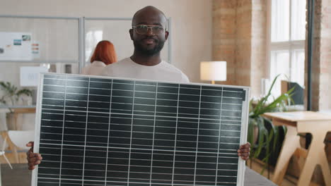 portrait of african american engineer with solar panel in office