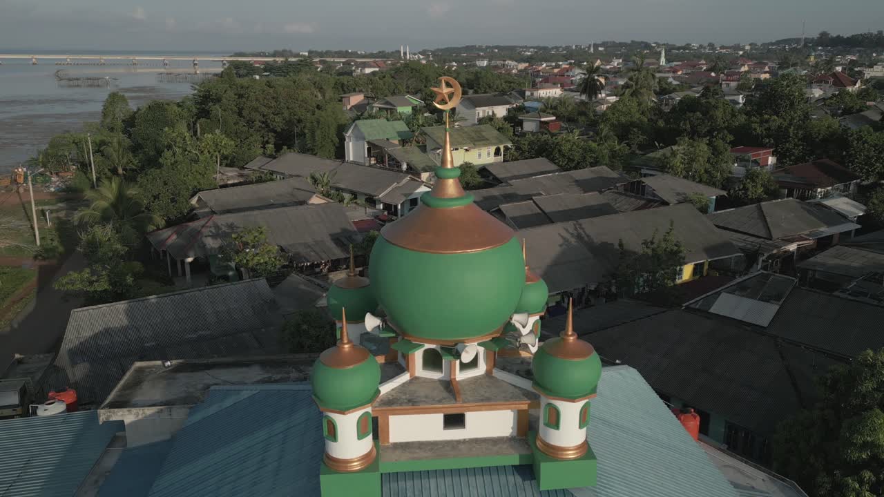 Cinematic drone pull-back from a green mosque dome, revealing the urban landscape of Tanjung Pinang, Indonesia - Tanjungpinang, Indonesia on Bintan Island