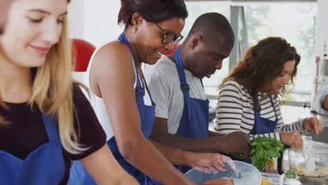 estudiantes adultos masculinos y femeninos preparando ingredientes para un plato en la clase de cocina de la cocina