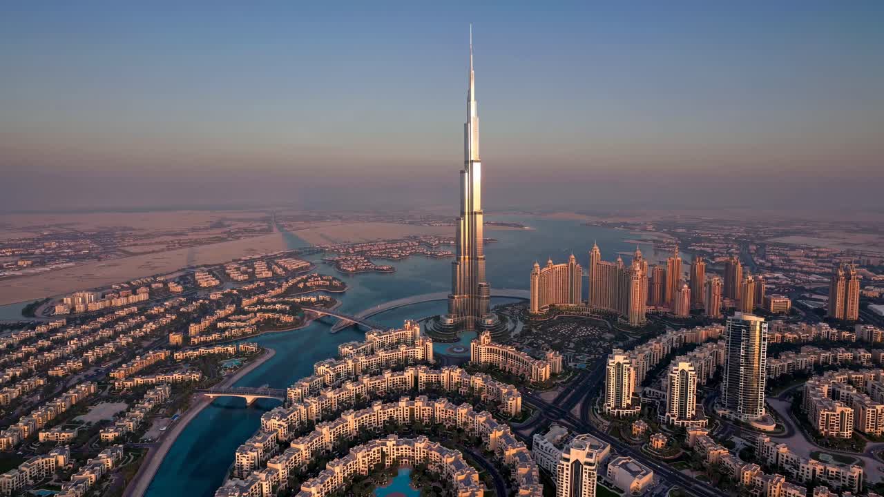 Aerial view of a futuristic cityscape at sunset, featuring a towering skyscraper