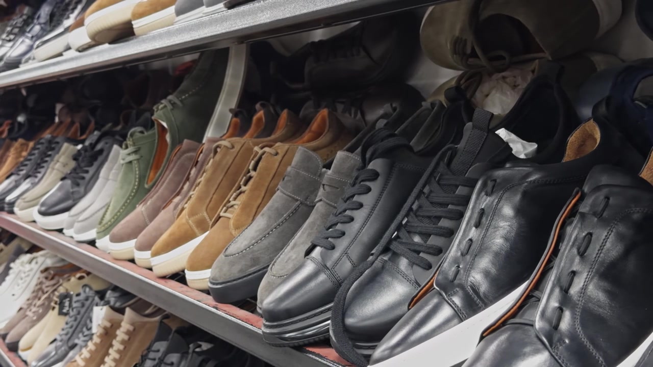 Hochwertige 4K-Nahaufnahme von Premium-Herren-Ledersneakern und klassischen Schuhen in einem Ladenregal. Präsentiert elegantes Schuhdesign, Handwerkskunst und eine Modekollektion für den Einzelhandel.