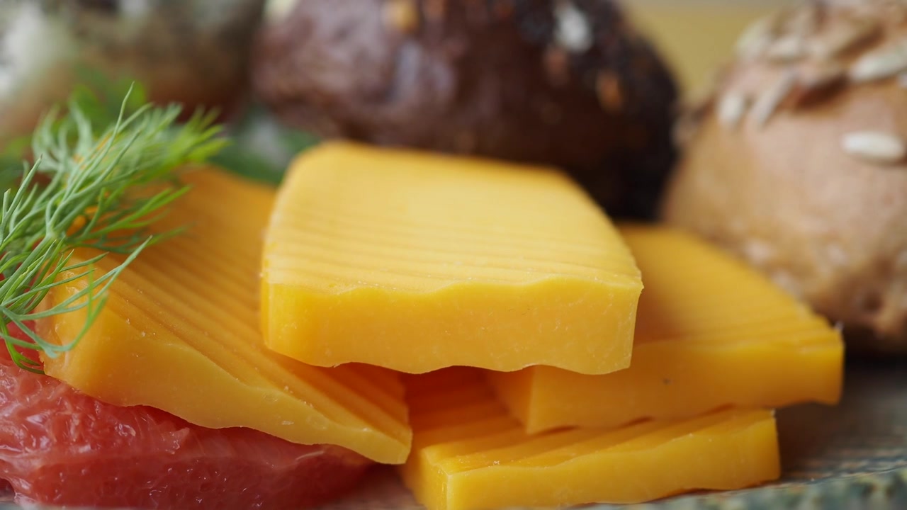 Gros plan sur du fromage jaune tranché avec du pamplemousse et des petits pains