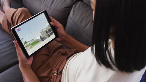 Composite-of-woman-on-couch-at-home-watching-athletics-high-jump-event-on-tablet