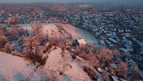 Aerial-view-flying-over-snowy-vinyards-'weinberge'-towards-a-church-of-Winterthur,-Canton-Zurich,-Switzerland