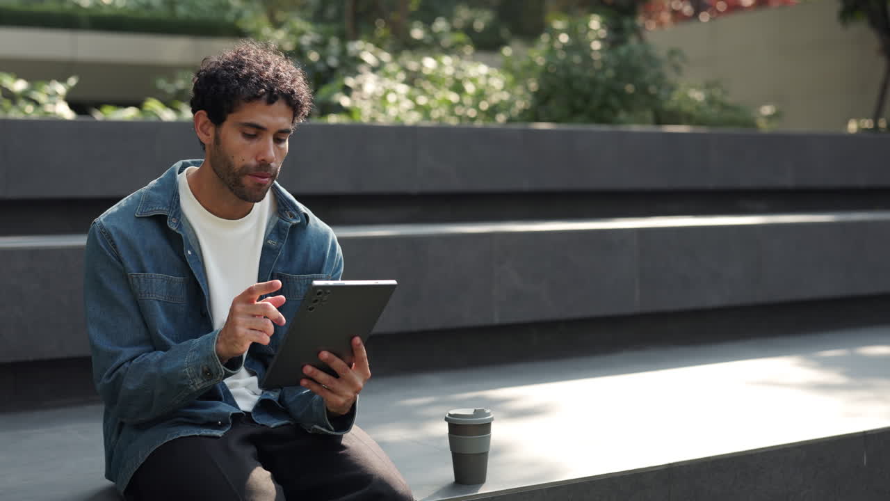 Young Man Using Digital Tablet Outdoors with Coffee