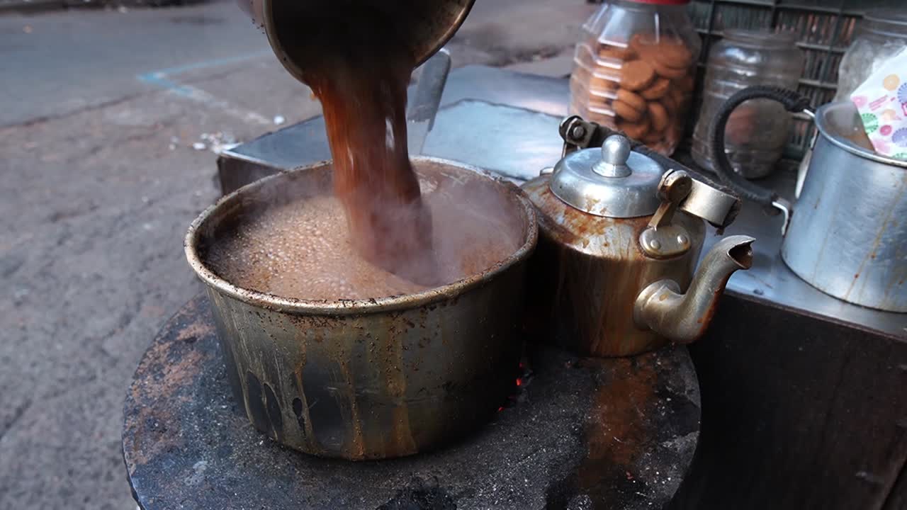 Stile tradizionale di bollitura delle foglie di tè per preparare il tè al latte in una bancarella a bordo strada a Calcutta, India