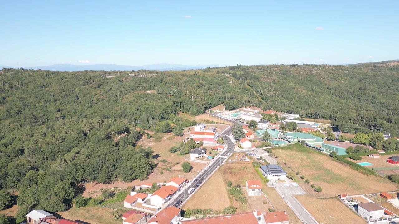 Vista aerea che segue la strada principale verso Luíntra, con case sparse, boschi e campagna aperta intorno a Nogueira de Ramuín nella regione della Ribeira Sacra di Ourense, Galizia, Spagna