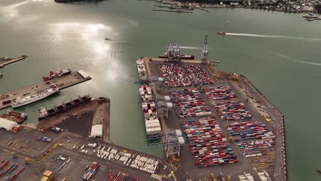 a smooth 4k 60fps drone shot flying backward over stacks of colorful cargo containers at the port of auckland, revealing the immense scale of the industrial area. perfect for logistics or trade themes