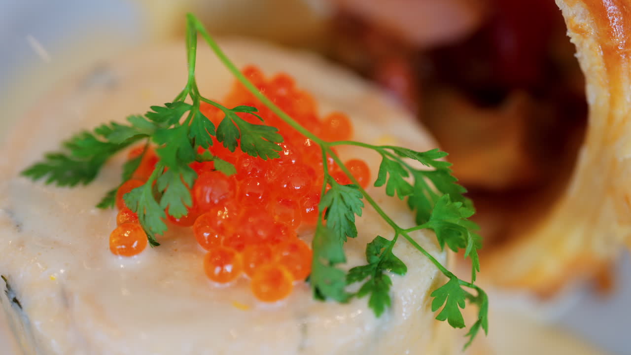 Close up of a fish mousse with salmon roe and puff pastry on a white plate at a restaurant