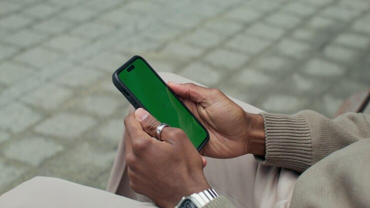 Person holding a smartphone with a green screen
