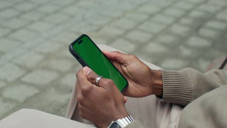 person holding a smartphone with a green screen