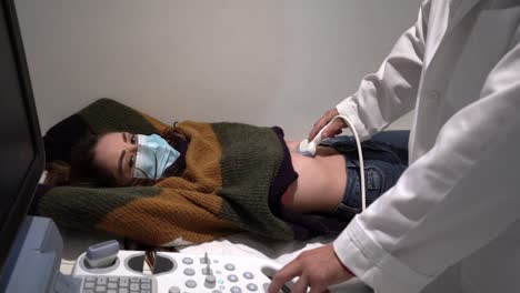 médico de cultivo examinando el estómago de una mujer con un escáner de ultrasonido