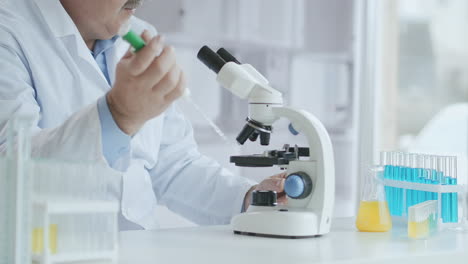 bearded caucasian male researcher wearing protective glasses and working with a microscope spbas. scientist using microscope in a laboratory. search for coronavirus vaccine. high quality 4k footage