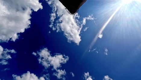 Tiro-De-ángulo-Bajo-Del-Movimiento-Del-Sol-A-Lo-Largo-Del-Cielo-Nublado-Dramático-Con-Movimiento-De-Nubes-Cumulus-Blancas-En-Timelapse