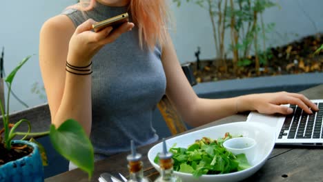 mujer joven usando teléfono móvil y portátil 4k
