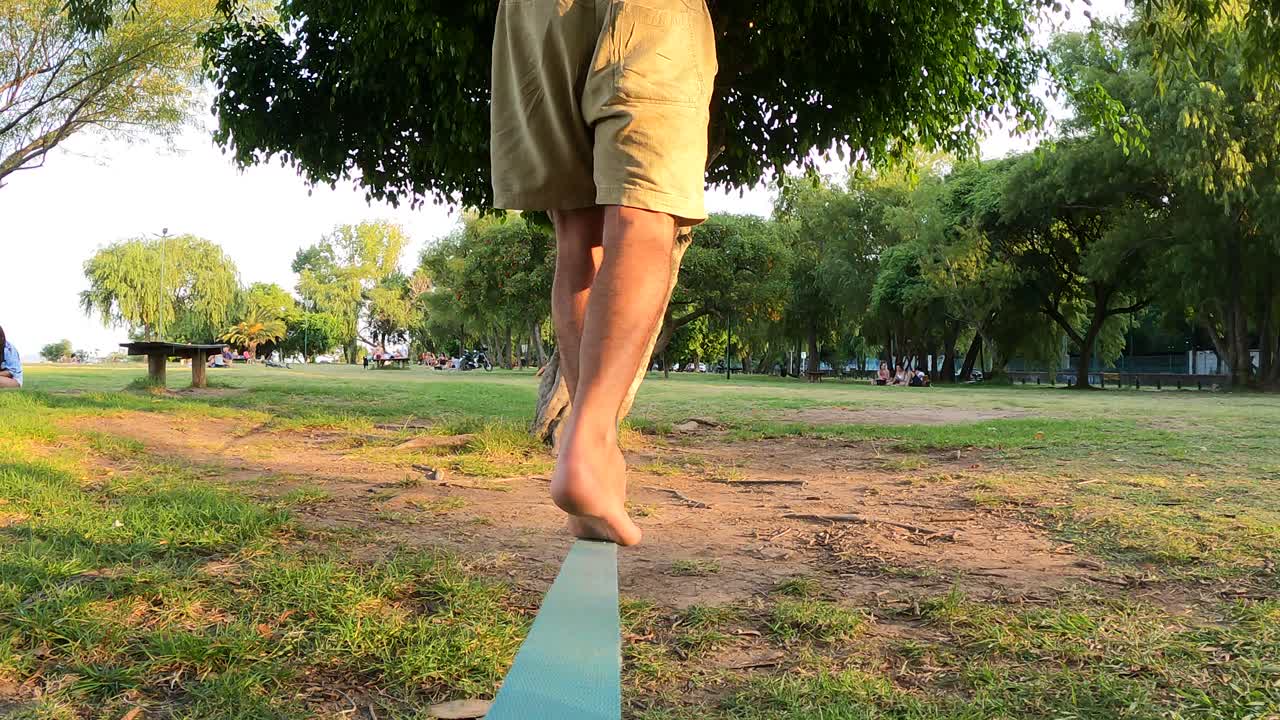 나무 슬랙 라인에서 한 발로 균형을 잡는 남자의 슬로우 모션