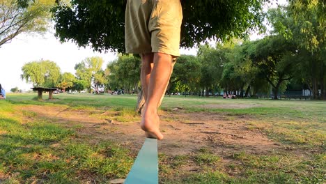 slow motion of man balancing on one foot at wooden slack line