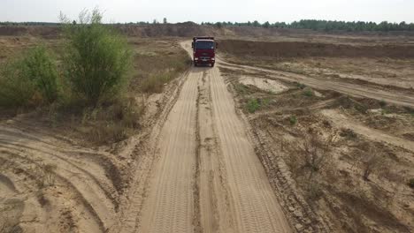 red truck driving on a dirt road in a quarry