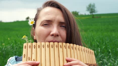 una mujer joven toca la flauta de pan en la naturaleza