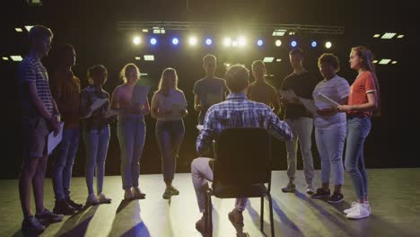 estudiantes preparándose antes de una actuación de la escuela secundaria con su maestro en un teatro escolar vacío