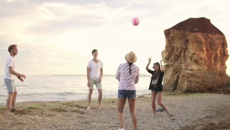 Jóvenes-Amigos-Alegres-Jugando-Voleibol-En-La-Playa-Junto-Al-Mar-Por-La-Noche.-Vacaciones-Activas.-Tiro-En-Cámara-Lenta