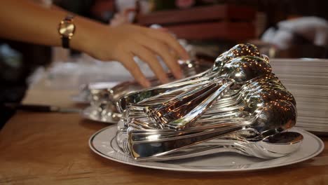 medium shot of metal forks and spoons placed on plates during social event catering in the evening