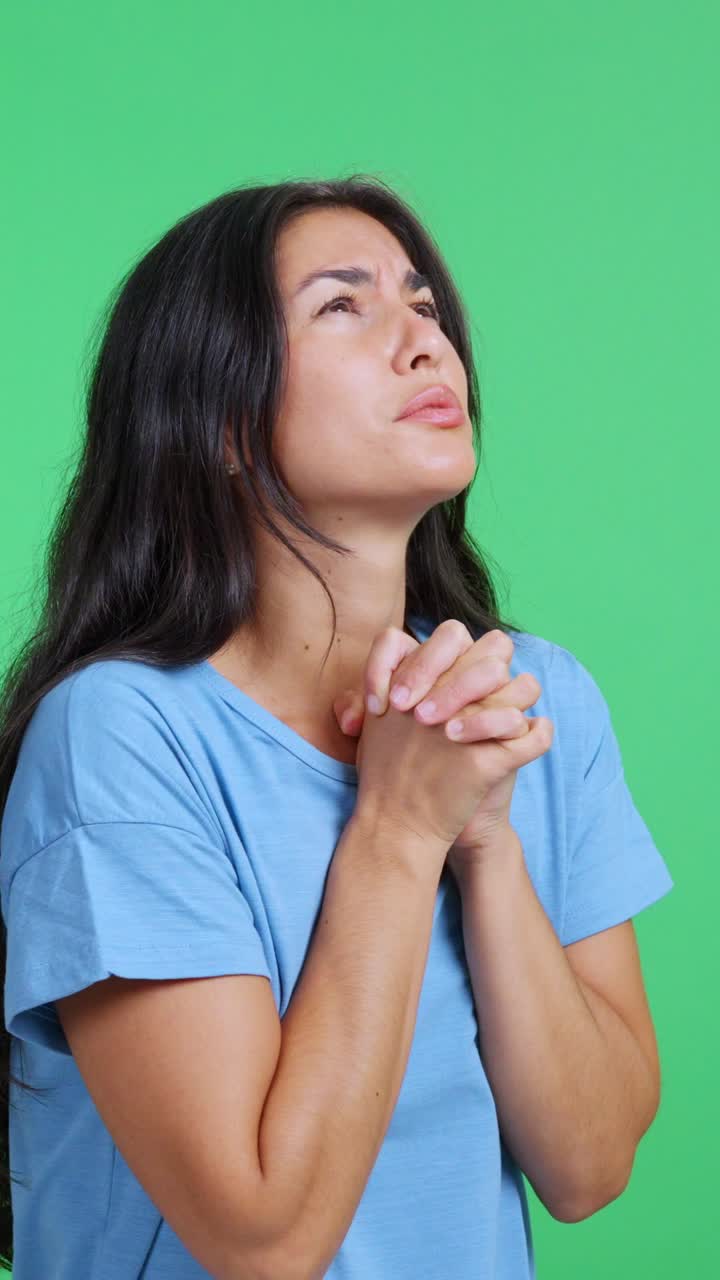 グリーンバックで希望を込めて祈る、ストレスを抱えた女性