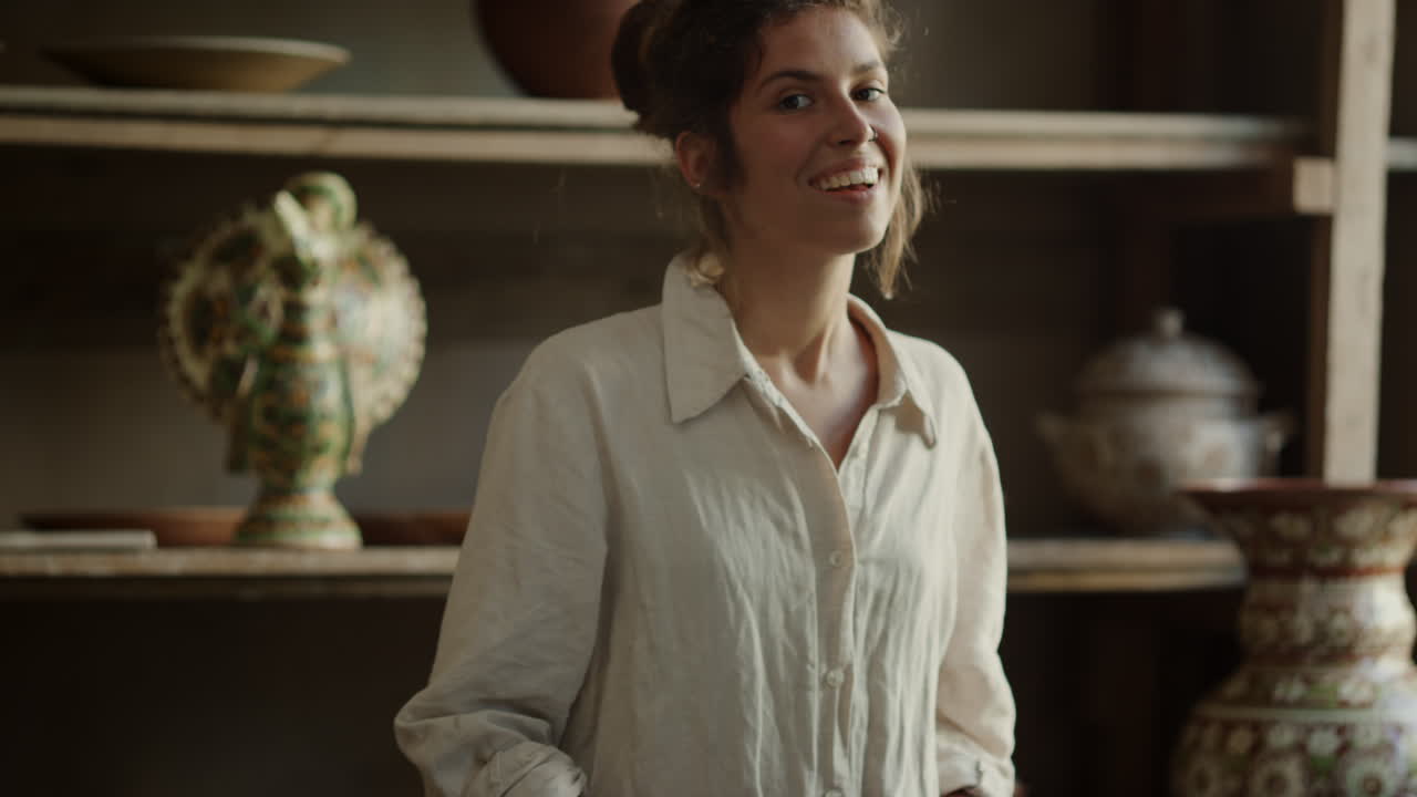 Una ceramista sorridente crea un prodotto in argilla in ceramica. Donna amichevole che realizza un manufatto.