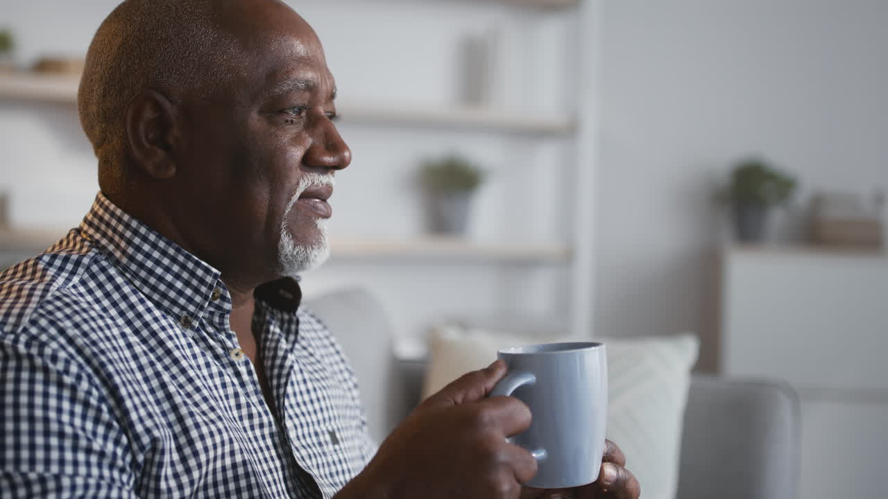 пожилой мужчина наслаждается напитком дома