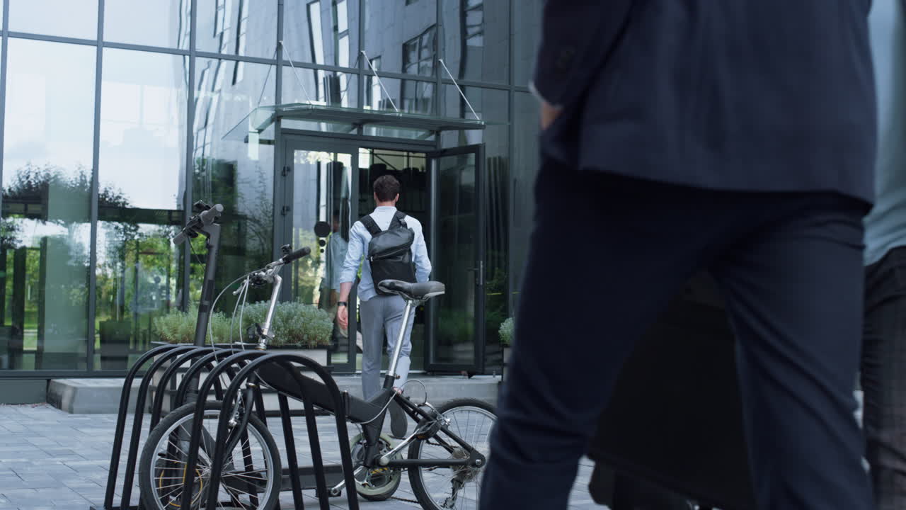 Professionisti che entrano a piedi in un edificio per uffici. Parcheggio condiviso in centro.