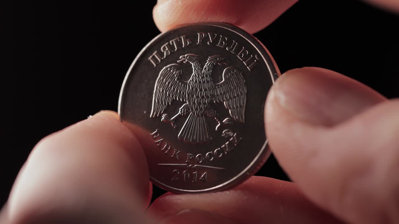 los dedos sostienen una moneda de 5 rublos rusos y la vuelven. concepto de depreciación, incumplimiento financiero o bancarrota. sanciones. intercambio de divisas. negocios con dinero. cabezas macro en fondo oscuro