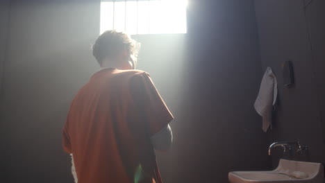 young female inmate brushing her teeth in sunlit prison cell