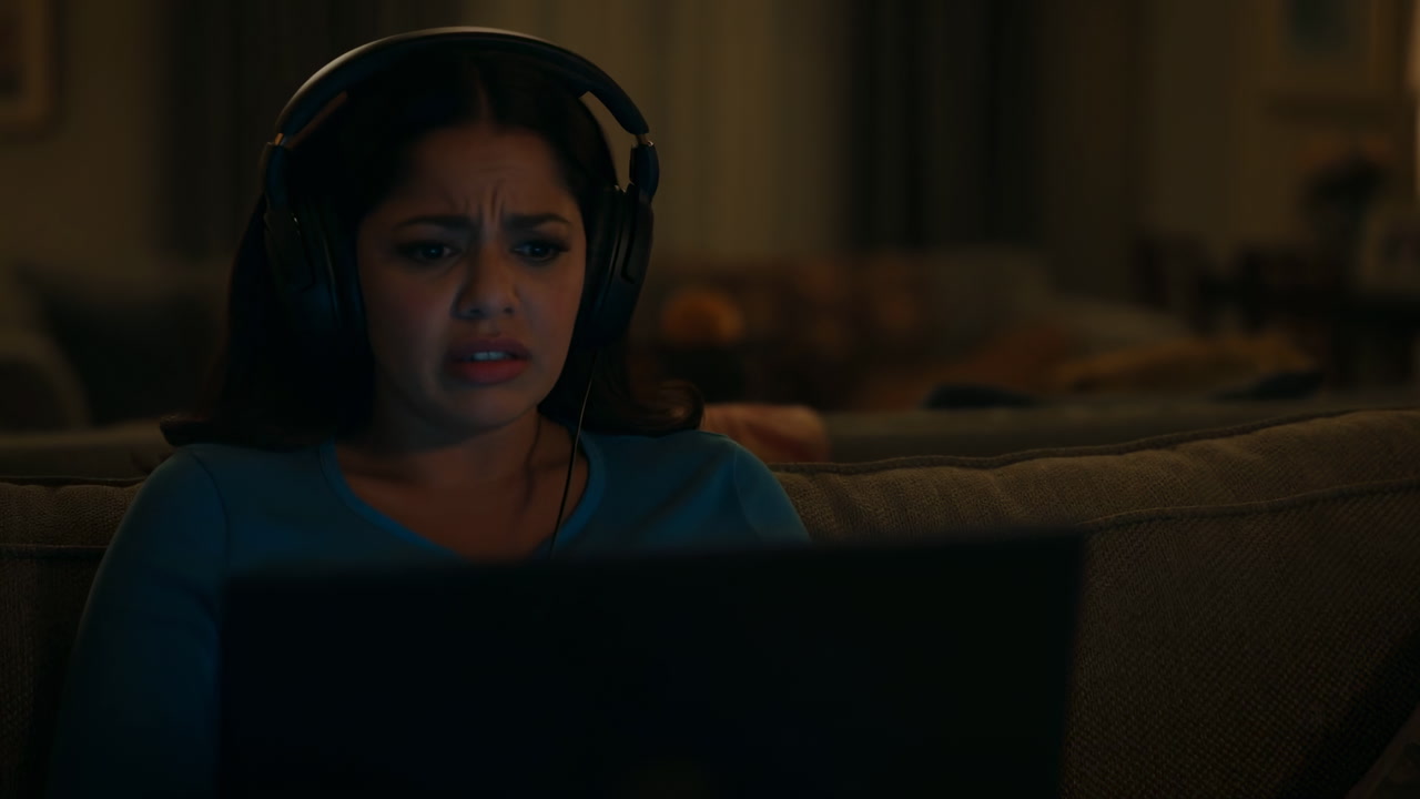 Late Night Asian Woman On Couch, Wearing Headphones, Staring At Laptop Screen, Concerned Expression, Dim