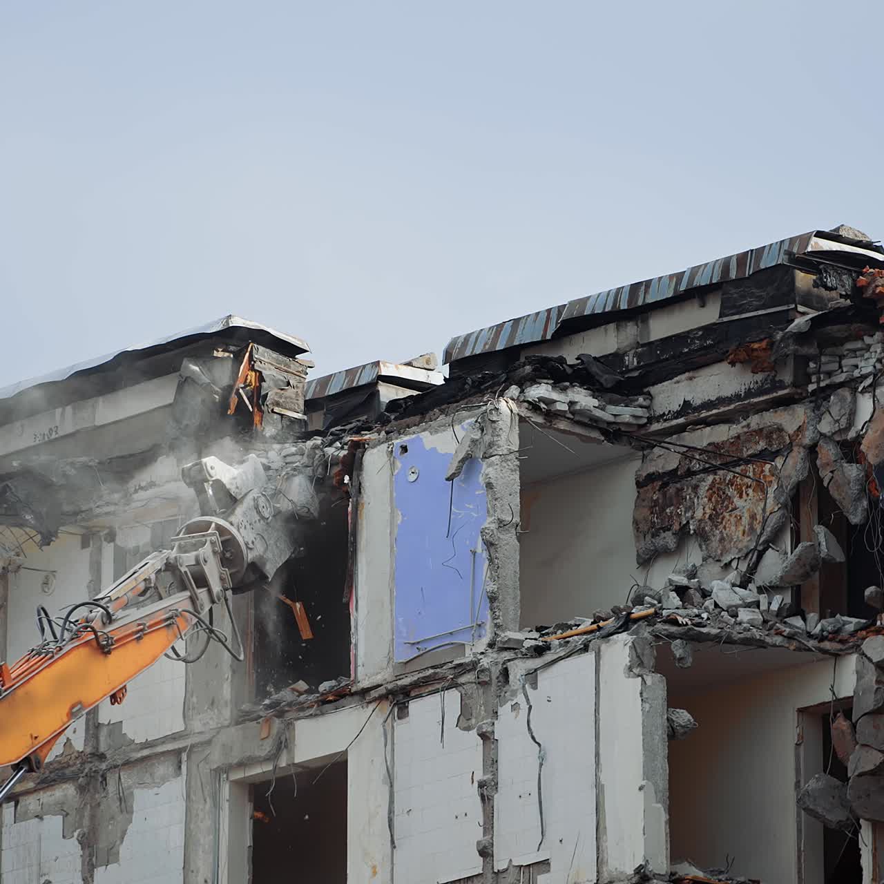 Destruction machine demolishes the ruined building. Pieces of concrete falling down from the roof of the destroyed house. Cleaning the site for the new construction