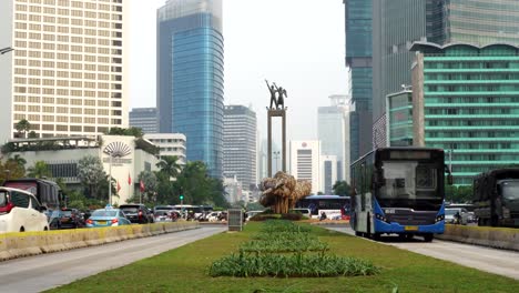 bustling urban street scene with selamat datang monument and traffic in jakarta, indonesia